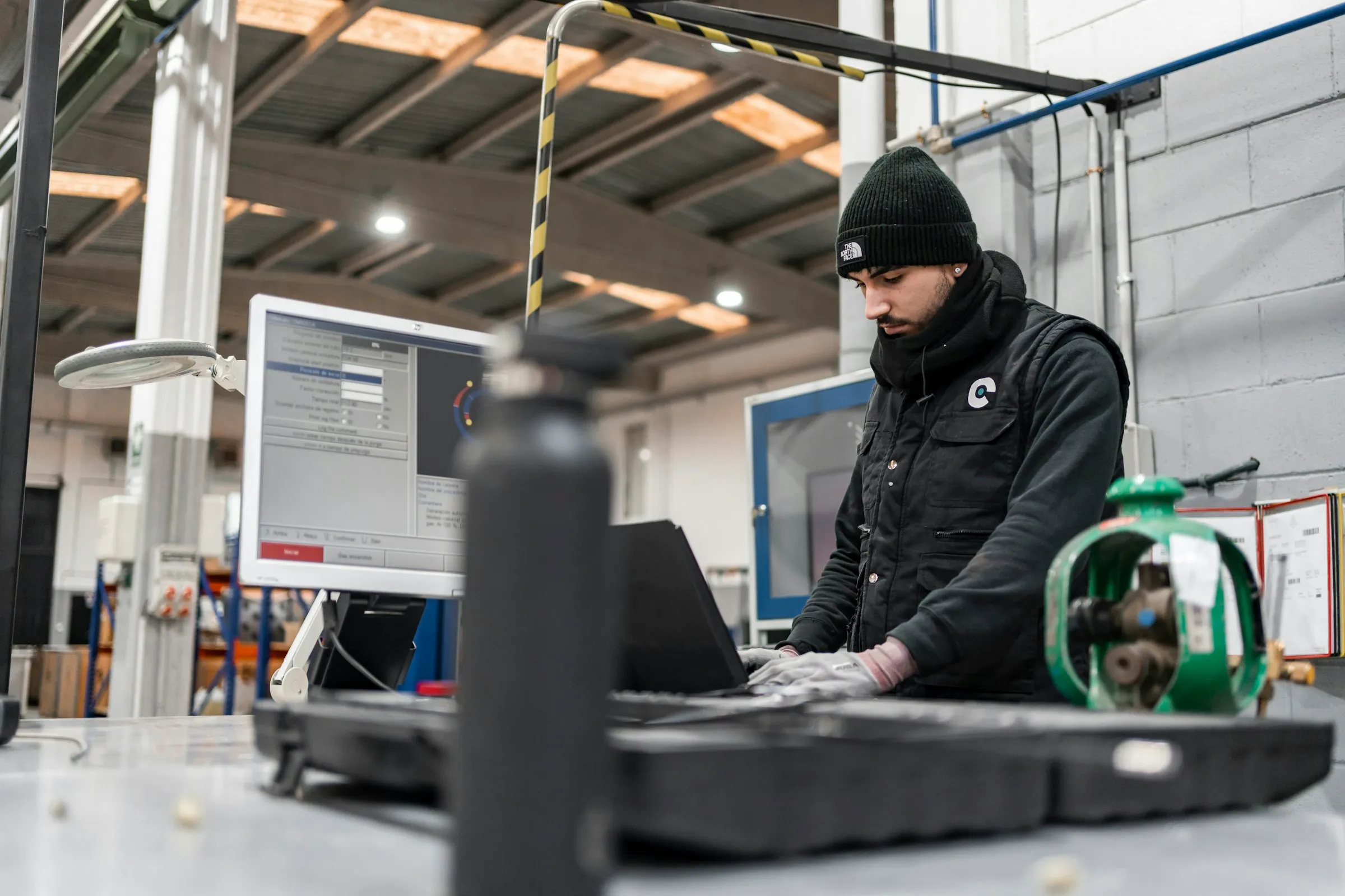 Techniker arbeitet an einem robusten Laptop an seinem Arbeitsplatz in einer Produktionshalle
