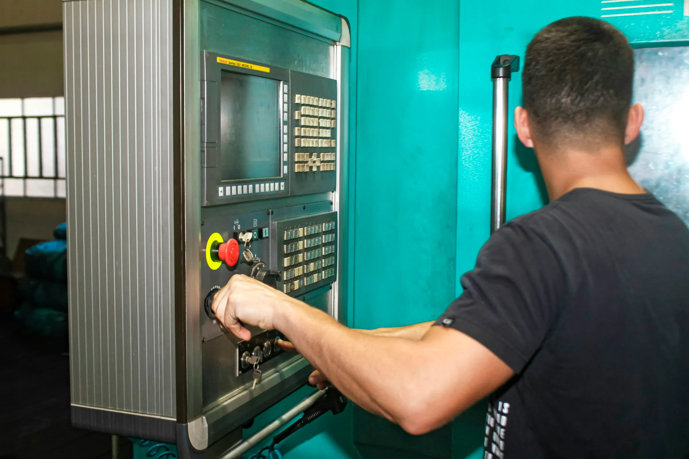 Bediener an der CNC-Steuerung einer Drehmaschine in einer Werkhalle