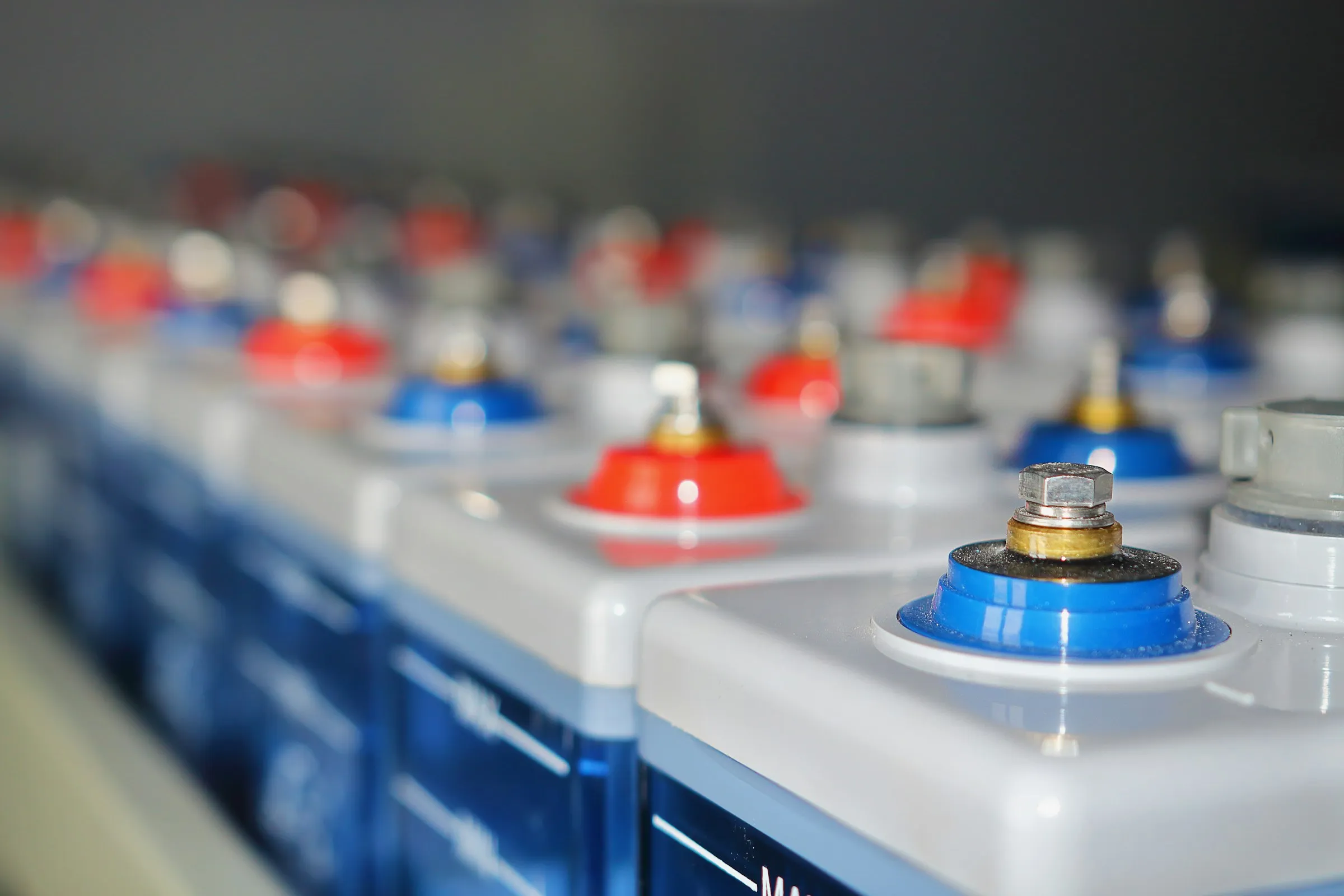 Reihen großer stationärer Batteriezellen mit roten und blauen Polen in einem Energiespeicher